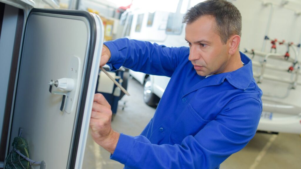 Technician in blue uniform repairing a caravan appliance