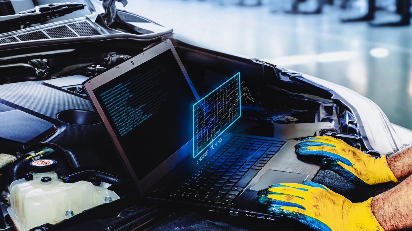 Mechanic using a laptop to perform engine tuning on a car